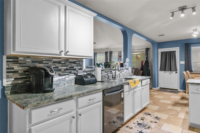 kitchen with tasteful backsplash, white cabinets, stainless steel dishwasher, and a sink