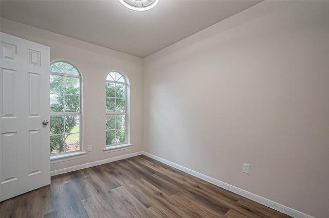 unfurnished room with plenty of natural light, dark wood finished floors, and baseboards