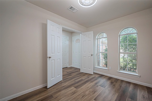 spare room featuring dark wood-style floors, baseboards, and visible vents