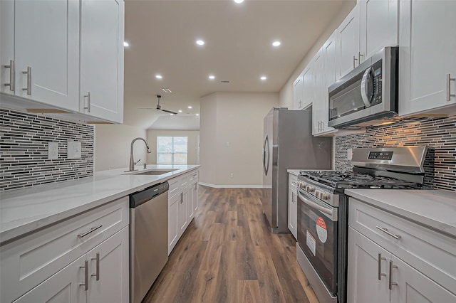 kitchen with stainless steel appliances, dark wood-style flooring, a sink, white cabinetry, and backsplash