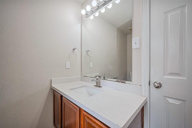 bathroom with a textured wall and vanity