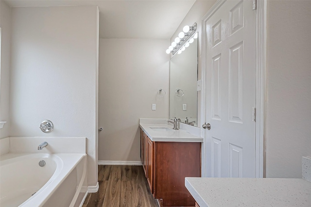 bathroom with wood finished floors, vanity, baseboards, and a bath