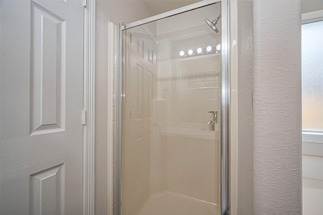 full bathroom with a shower stall and a textured wall