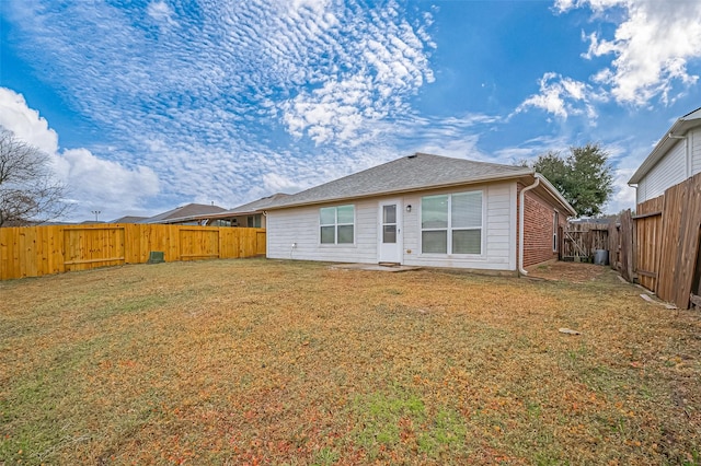 back of house featuring a fenced backyard, a lawn, and roof with shingles