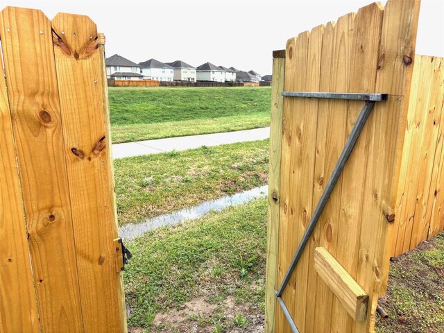 view of gate with a residential view and a yard