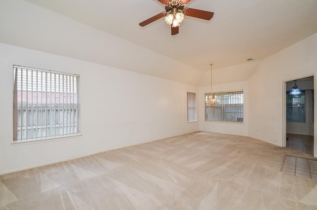 carpeted spare room featuring vaulted ceiling and ceiling fan with notable chandelier