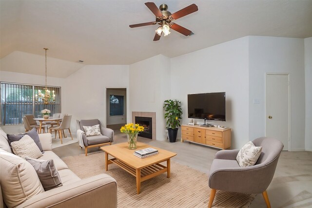 living area with a fireplace, visible vents, vaulted ceiling, and ceiling fan with notable chandelier