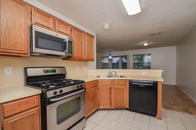 kitchen featuring visible vents, a peninsula, stainless steel appliances, light countertops, and a sink