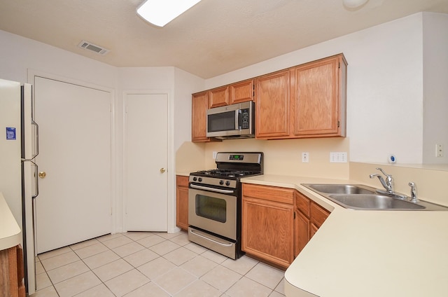 kitchen with visible vents, appliances with stainless steel finishes, light countertops, a sink, and light tile patterned flooring