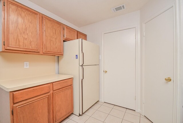 kitchen featuring light countertops, freestanding refrigerator, visible vents, and light tile patterned flooring