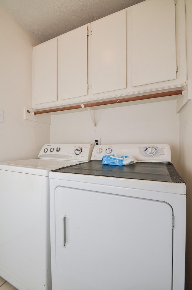 laundry room featuring a textured ceiling, independent washer and dryer, and cabinet space