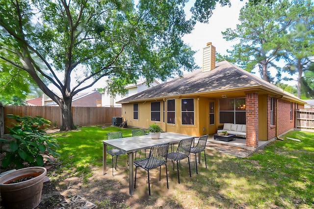 back of house featuring a fenced backyard, brick siding, outdoor lounge area, a lawn, and a chimney