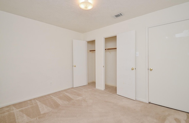 unfurnished bedroom with light carpet, visible vents, and a textured ceiling