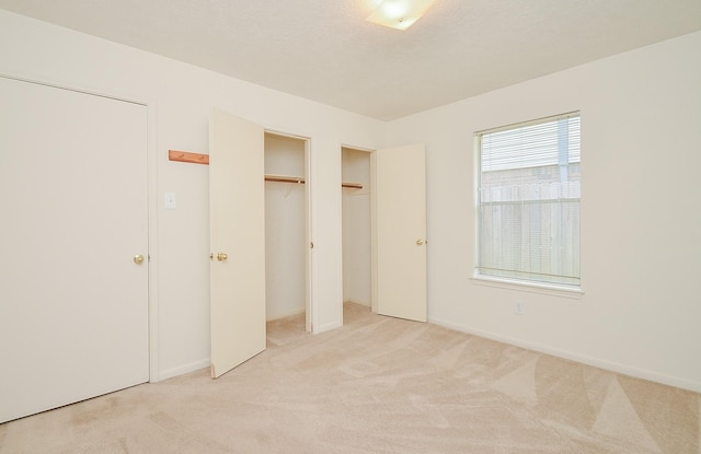 unfurnished bedroom with a closet, a textured ceiling, and light colored carpet