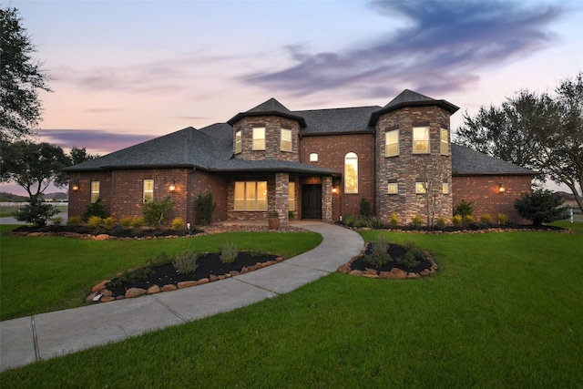 view of front of home featuring a front lawn, brick siding, and stone siding