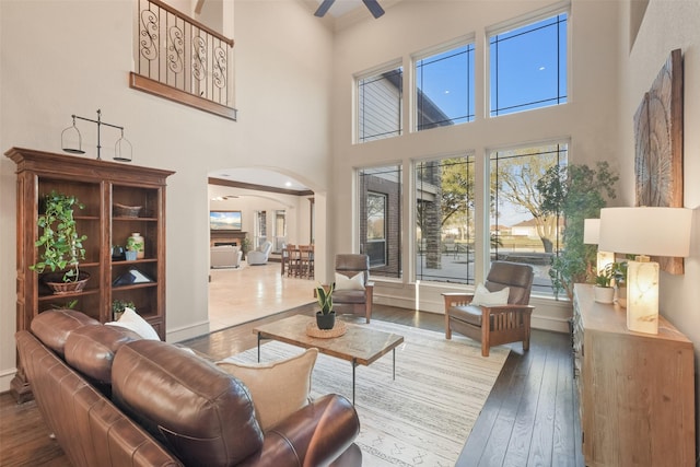 living area featuring arched walkways, plenty of natural light, ceiling fan, and wood-type flooring