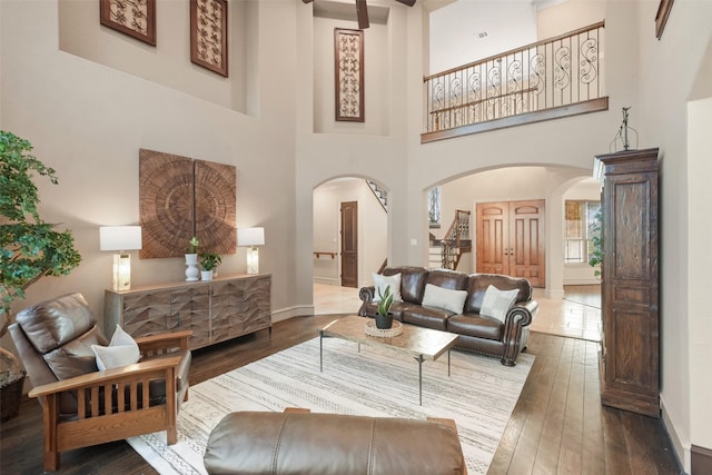 living room featuring visible vents, baseboards, arched walkways, and wood-type flooring