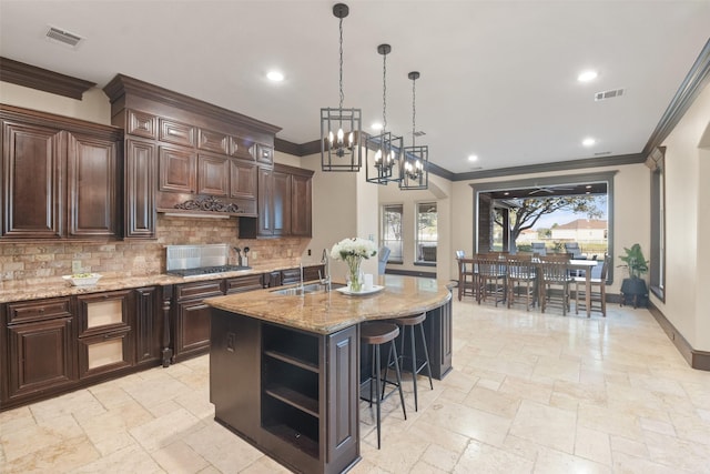 kitchen featuring visible vents, a sink, open shelves, backsplash, and stone tile flooring