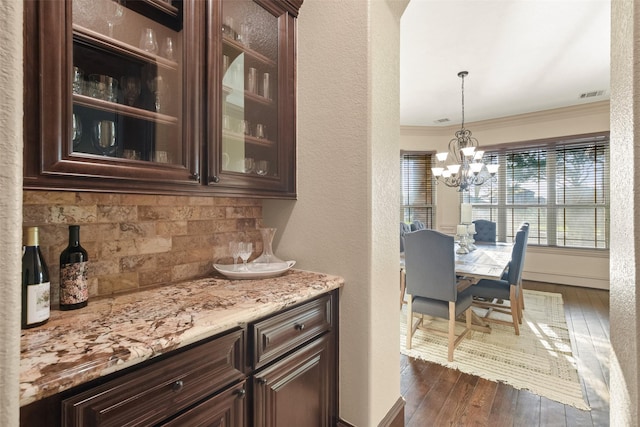 kitchen with visible vents, dark wood-type flooring, dark brown cabinetry, and crown molding