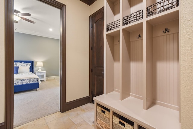 mudroom with light carpet, ornamental molding, a ceiling fan, stone finish flooring, and baseboards