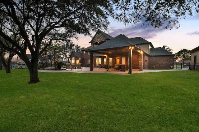 back of property featuring a patio area, a lawn, and brick siding