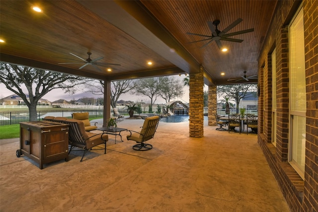 view of patio / terrace with a water view, a ceiling fan, and fence