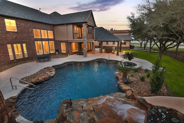 pool at dusk with an outdoor pool, a patio, fence, and a lawn