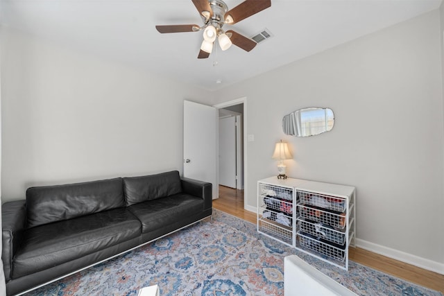 living room featuring visible vents, a ceiling fan, baseboards, and wood finished floors