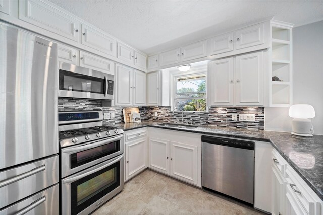 kitchen featuring white cabinetry, open shelves, stainless steel appliances, and a sink