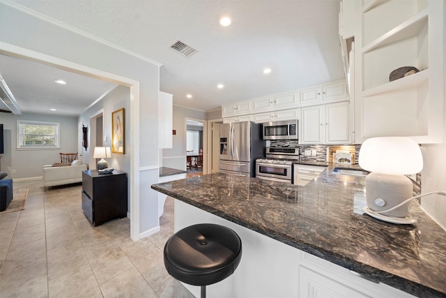 kitchen with visible vents, backsplash, dark stone counters, appliances with stainless steel finishes, and a peninsula