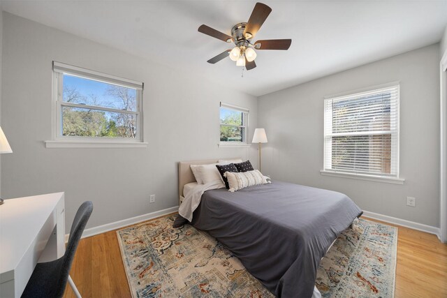 bedroom featuring baseboards, wood finished floors, and a ceiling fan