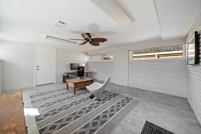 office area with a ceiling fan, visible vents, and brick wall