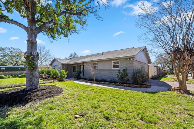 ranch-style home with a front yard, fence, brick siding, and driveway