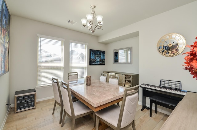 dining room featuring baseboards, light wood-type flooring, visible vents, and an inviting chandelier