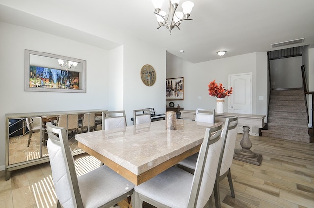 dining room featuring a chandelier, light wood finished floors, stairs, and visible vents