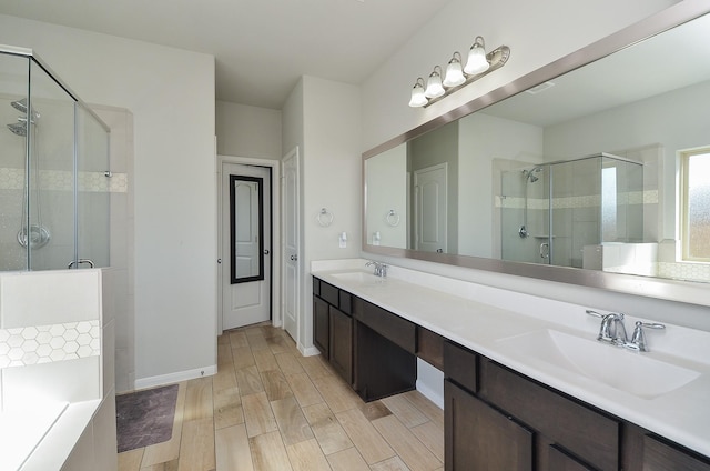 bathroom with double vanity, wood finished floors, a sink, and a shower stall