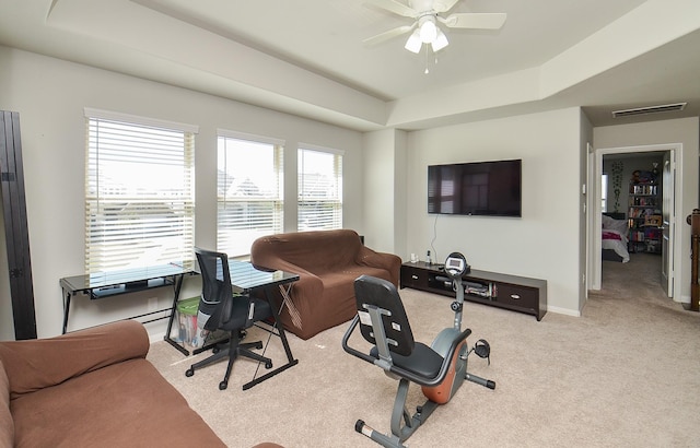 carpeted office space featuring baseboards, a raised ceiling, visible vents, and a ceiling fan