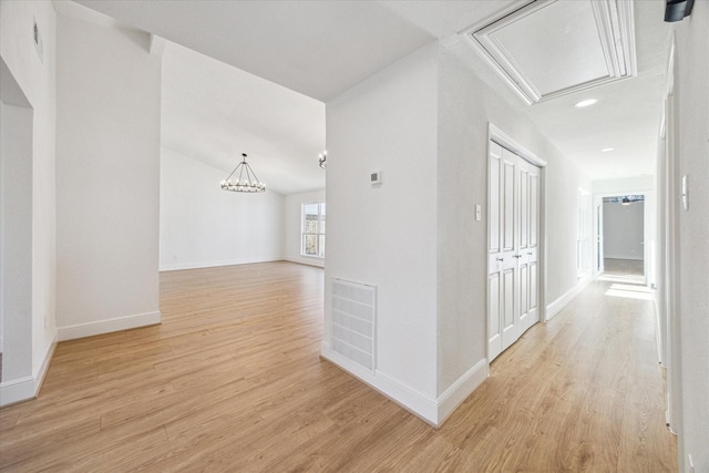 corridor with light wood-style floors, attic access, visible vents, and baseboards