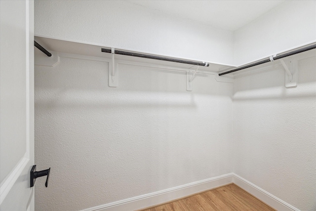 walk in closet with light wood-style floors