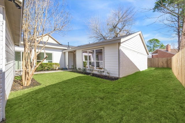 rear view of property with a yard, brick siding, and fence