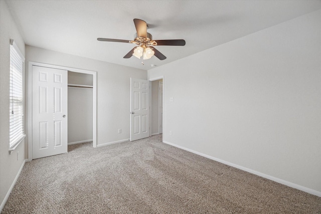 unfurnished bedroom with light carpet, ceiling fan, a closet, and baseboards