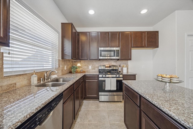 kitchen with tasteful backsplash, appliances with stainless steel finishes, light stone countertops, a sink, and recessed lighting