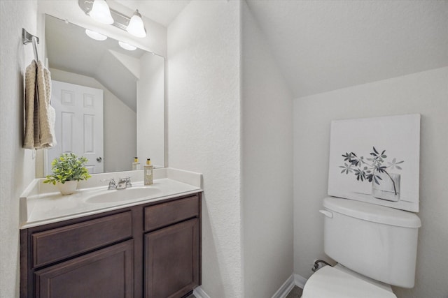 bathroom featuring toilet, baseboards, vaulted ceiling, and vanity