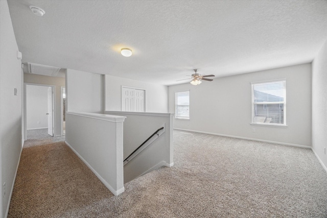 hallway featuring a textured ceiling, carpet floors, an upstairs landing, and baseboards