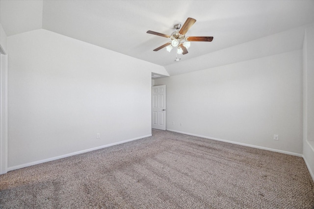 empty room featuring lofted ceiling, carpet, baseboards, and ceiling fan