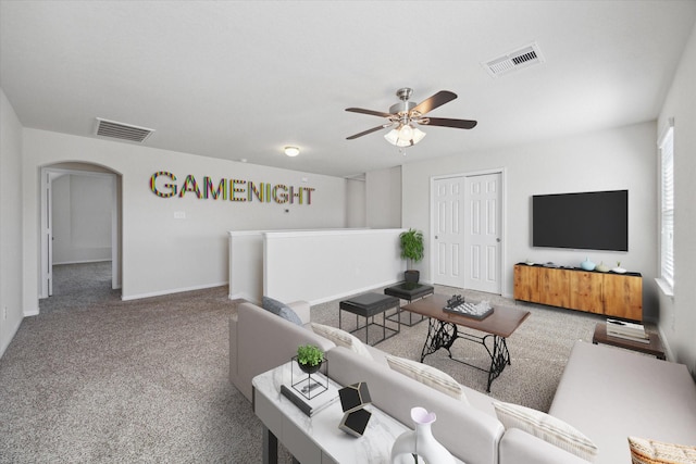 carpeted living area featuring ceiling fan, visible vents, arched walkways, and baseboards