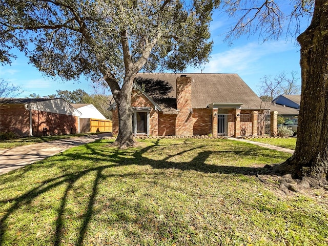 view of front of home with brick siding, a chimney, a front yard, and fence