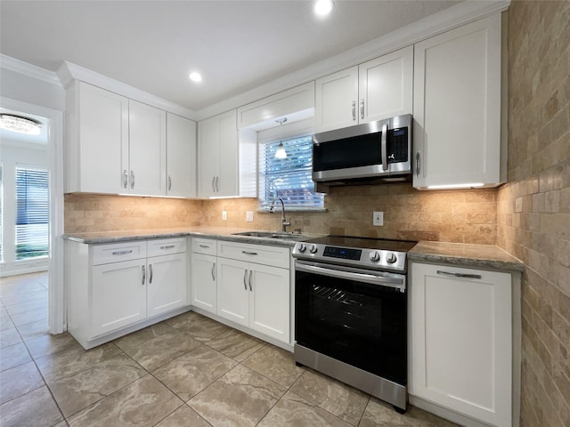 kitchen featuring crown molding, decorative backsplash, appliances with stainless steel finishes, white cabinetry, and a sink