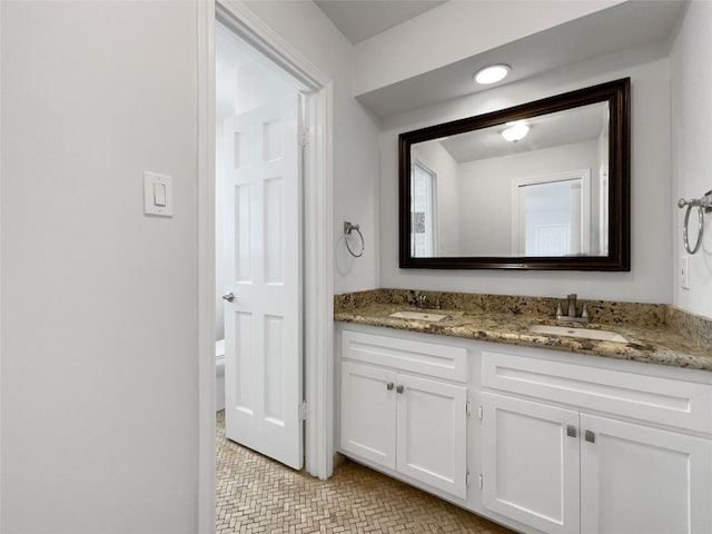 bathroom with a sink, toilet, and double vanity