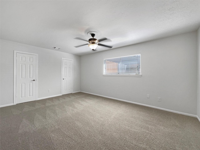 carpeted spare room with visible vents, baseboards, a textured ceiling, and ceiling fan